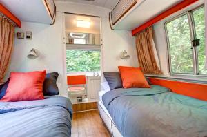two beds in a small room with two windows at Glamping 1970 American Airstream motorhome in Ponsanooth