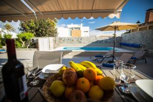 a bowl of fruit on a table with a bottle of wine at Villa Jandia Modern new apartment Morro Jable Private heated pool big terrace and parking in Morro del Jable
