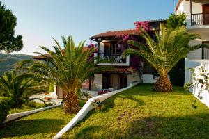 une maison avec deux palmiers dans la cour dans l'établissement Villa Anna Maria, à Agia Paraskevi