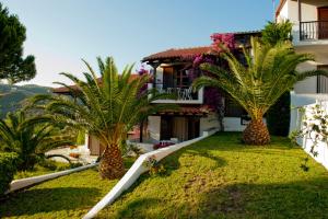 a house with two palm trees in the yard at Villa Anna Maria in Agia Paraskevi