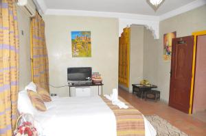 1 dormitorio con 1 cama blanca y TV en Riad Mhidou, en Marrakech