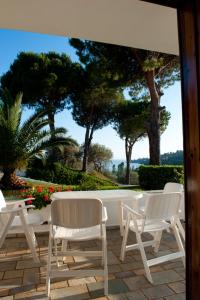 a patio with white chairs and a table and trees at Villa Anna Maria in Agia Paraskevi