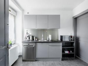 a kitchen with white cabinets and a microwave at Comfort Stay Basel Airport 1B46 in Saint-Louis