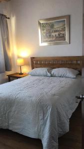 Un dormitorio con una cama blanca con una foto en la pared en Casa Las Nubes en el Centro de Tequisquiapan 6 personas en Tequisquiapan