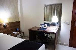 a hotel room with a desk with a laptop on it at Hotel D'Luca in Cuiabá