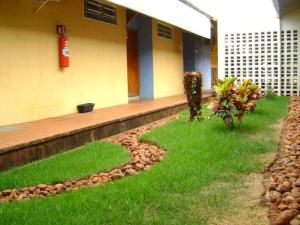 a house with a yard with grass and a building at Hotel Urubupunga in Ilha Solteira