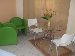 a dining room with a glass table and green chairs at Hotel Urubupunga in Ilha Solteira