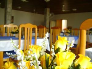 a vase of yellow flowers on a table with chairs at Hotel Urubupunga in Ilha Solteira