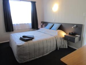 a bedroom with a bed with blue pillows and a window at Beachside Sunnyvale Motel in Picton