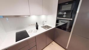 White Pearl Apartment 0.10 في تيميندورفير ستراند: مطبخ أبيض مع حوض وميكروويف