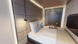 ein kleines Schlafzimmer mit einem weißen Bett und einem TV in der Unterkunft White Pearl Apartment 0.11 in Timmendorfer Strand