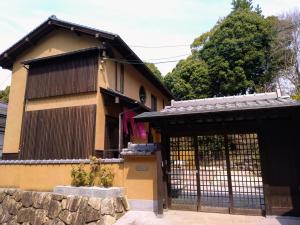 ein Haus mit einem Tor und einer Steinmauer in der Unterkunft Miyajima Fujinoya Female Only in Miyajima