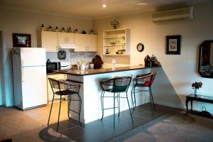 a kitchen with a bar with stools and a refrigerator at Rosewood Park Guest Suite in Yarragon