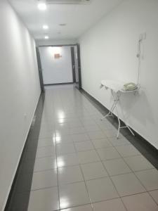 a hallway with a white floor and a table and a door at Linkway Hotel in Nusajaya