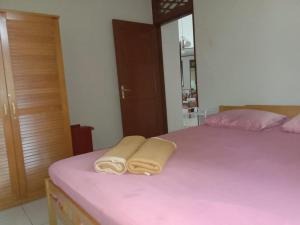 1 dormitorio con 1 cama rosa y 2 toallas en Villa Bougenville 2, Jalan Raya Kota Bunga, en Puncak