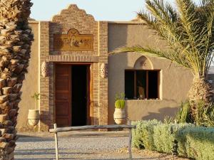 a brick building with a door and a bench in front at Tifina Caravanserail d'Arfoud in Erfoud
