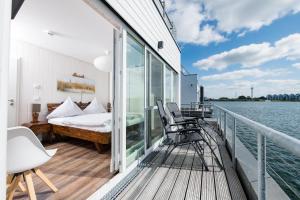 einen Balkon mit einem Schlafzimmer und einem Bett auf einem Boot in der Unterkunft Schwimmendes Haus Marina Rainbow in Olpenitz