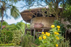 a house with a thatched roof with yellow flowers at Hostal La Media Luna Palomino in Palomino