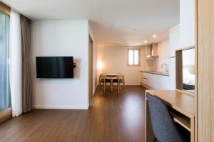 a kitchen and a living room with a television on a wall at Lemain Hotel in Jeju