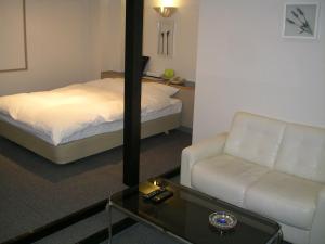 Niseko Youraku Hotel في نيسيكو: غرفه فندقيه بسرير واريكه وطاولة