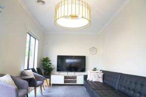 a living room with a couch and a flat screen tv at Luxury 9 BRM house in Melbourne in Laverton