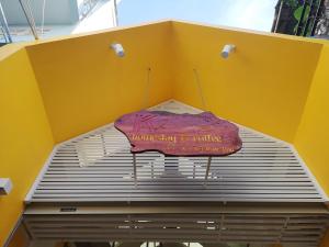 un parapluie rose assis au-dessus d'un mur jaune dans l'établissement K2 Homestay & Coffee, à Cần Thơ