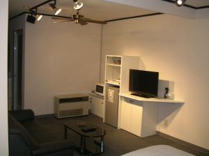 un salon avec une télévision et un bureau avec un ordinateur dans l'établissement Niseko Youraku Hotel, à Niseko