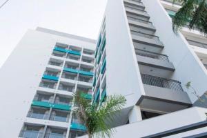 a tall white building with palm trees in front of it at Studio Wise Anhembi in São Paulo