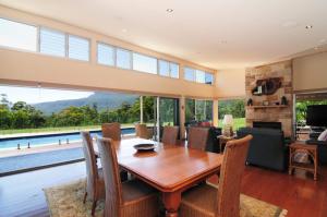 a dining room with a table and chairs and a pool at Bottlebrush Lodge Great views and a pool in Upper Kangaroo River