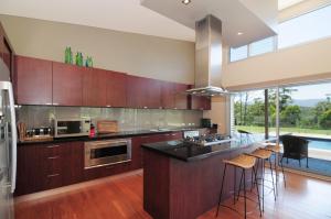 a kitchen with wooden cabinets and a counter with bar stools at Bottlebrush Lodge Great views and a pool in Upper Kangaroo River