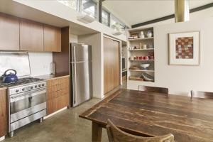 a kitchen with a wooden table and a stainless steel refrigerator at Bundaleer Architect designed stunning views in Kangaroo Valley