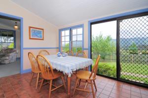 une salle à manger avec une table et des chaises dans l'établissement Magnolia Cottage Kangaroo Valley, à Barrengarry