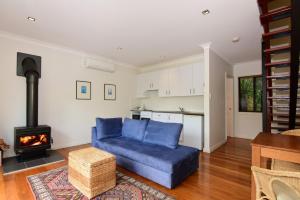 a living room with a blue couch and a stove at Cloudsong Chalet 1 Close to the village centre in Kangaroo Valley