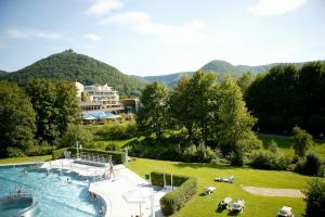 a resort with a large swimming pool with mountains in the background at Hotel Graf Eberhard in Bad Urach