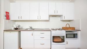 a kitchen with white cabinets and a stove top oven at Cloudsong Chalet 3 Close to the village centre in Kangaroo Valley