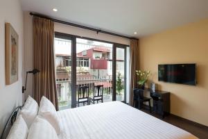 a bedroom with a large bed and a large window at Centraltique Downtown - Bespoke Colonial House Near Hoan Kiem Lake in Hanoi