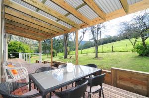 a patio with a table and chairs on a wooden deck at Nellsville Cottage Kangaroo Valley in Upper Kangaroo River