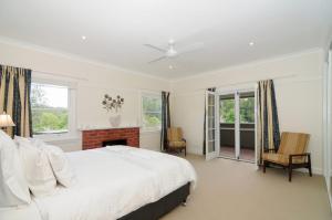 a white bedroom with a bed and a fireplace at Nellsville Cottage Kangaroo Valley in Upper Kangaroo River