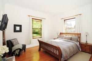 1 dormitorio con 1 cama, 1 silla y ventanas en Rivermist Luxury 6 bedrooms and 6 bathrooms en Kangaroo Valley