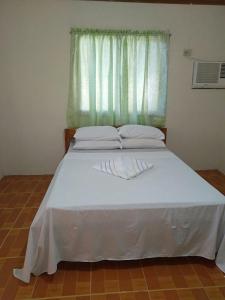 a bed in a room with a window with white sheets at Gold Star Inn in Siquijor