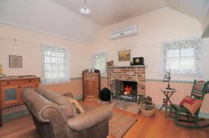 a living room with a couch and a fireplace at The Settlers Cottage Kangaroo Valley in Barrengarry