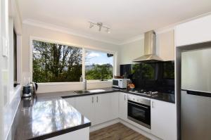 a kitchen with white cabinets and a large window at Treetops - Three bedroom home with great views, in the village! in Kangaroo Valley +11 photos
