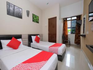 2 Betten in einem Zimmer mit roter und weißer Bettwäsche in der Unterkunft Super OYO 1153 Heaven Hill Hotel 1 in Cameron Highlands