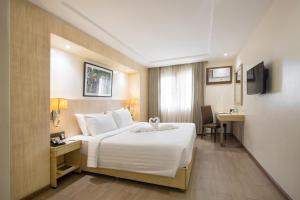 a hotel room with a bed and a desk at Golden Prince Hotel & Suites in Cebu City