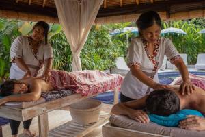 two women are giving a man a massage at United Colors of Bali in Canggu