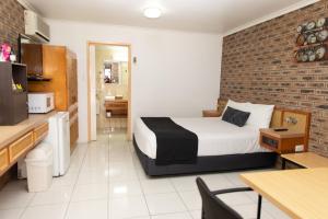 Habitación de hotel con cama y pared de ladrillo en Lantern Motor Inn en Mackay