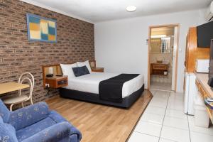 1 dormitorio con cama y pared de ladrillo en Lantern Motor Inn, en Mackay