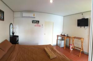 a bedroom with a bed and a television on the wall at Aroonsri Thara in Ratchaburi