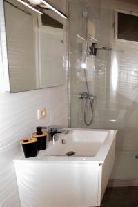 een witte badkamer met een wastafel en een douche bij De Zee in Oostende