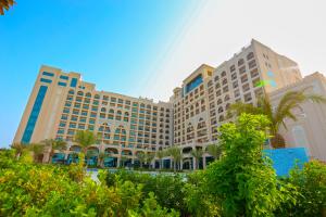 a large building with palm trees in front of it at Al Bahar Hotel & Resort in Fujairah